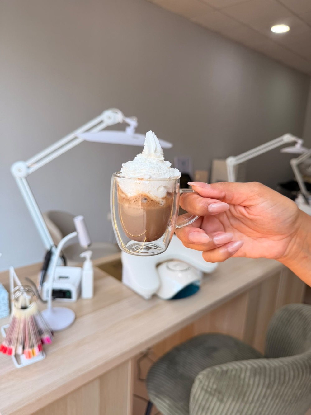 Cappuccino brasileño con nata servido en el salón, sobre la mesa de manicura