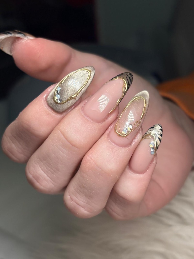 Uñas almendra con relieve dorado, efecto cat eye y print de cebra